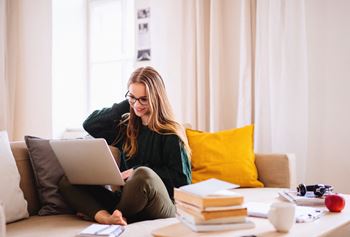 A young happy college female student sitting on sofa at home, using laptop when studying. at Renaissance Park Apartments, Davis, CA